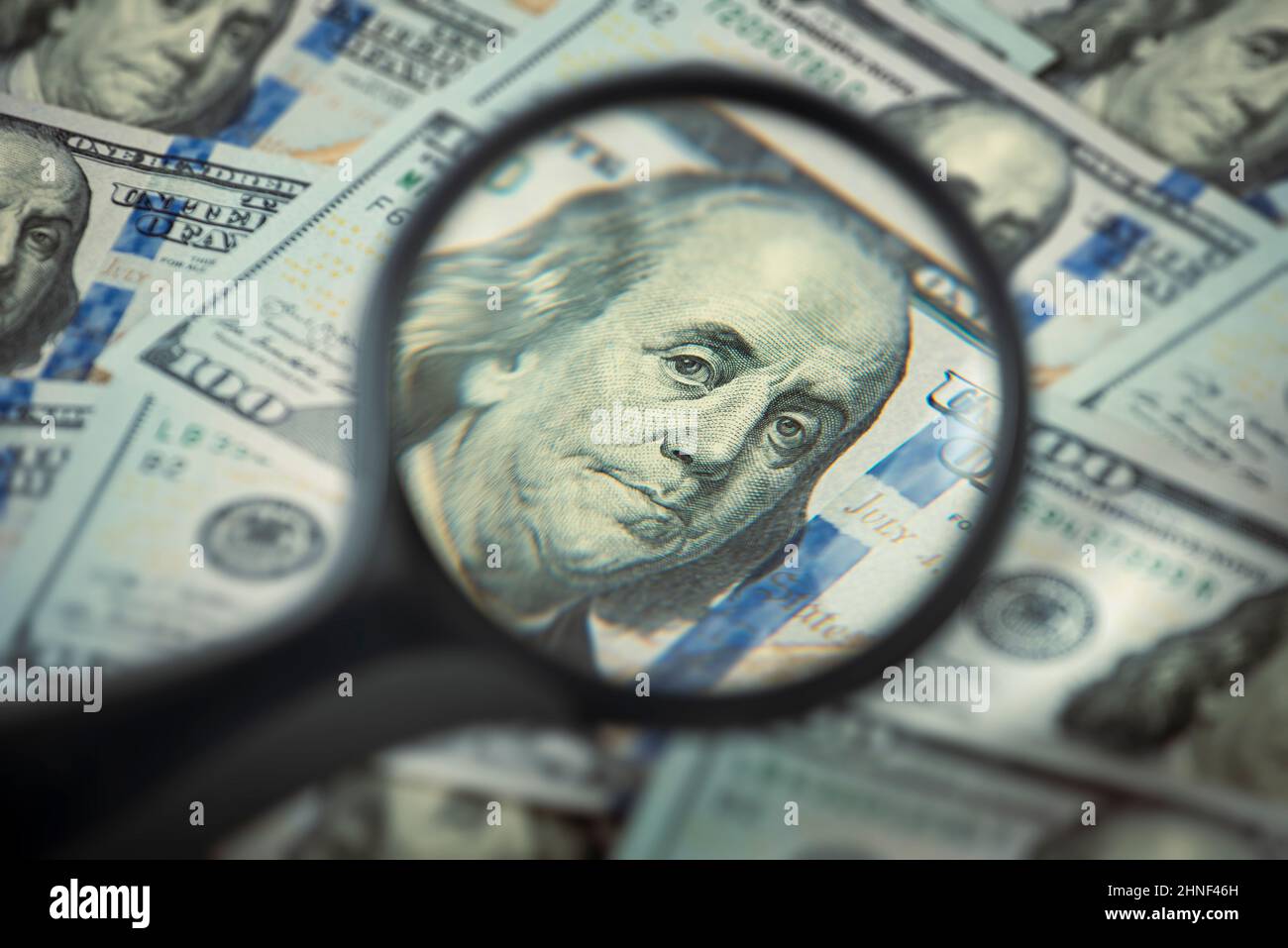 Finance and capital banking concept, Portrait of Benjamin Franklin in a magnifying glass, One hundred dollar bills Stock Photo