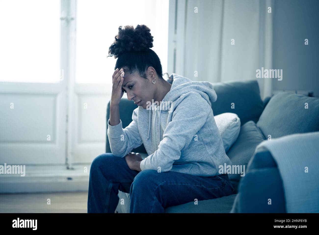 Depressed young attractive african american woman lying on sofa at home