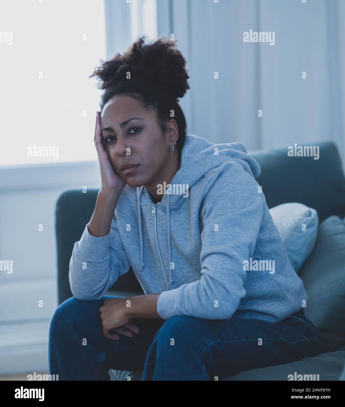 Young attractive african american woman lying at home living room couch feeling sad tired and worried suffering depression, distress and anxiety in me Stock Photo