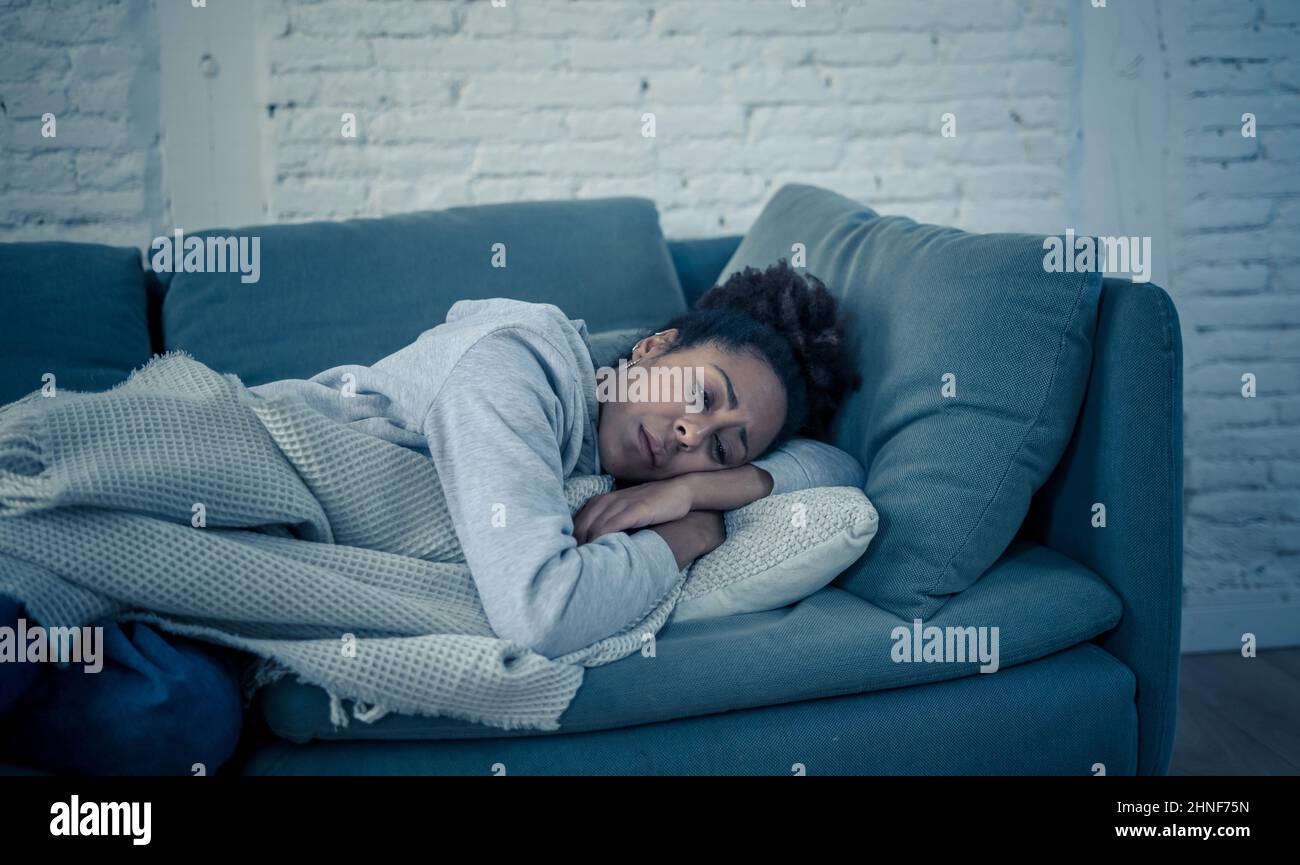 Depressed young attractive african american woman lying on sofa at home feeling sad tired and worried suffering depression stress and anxiety in menta Stock Photo