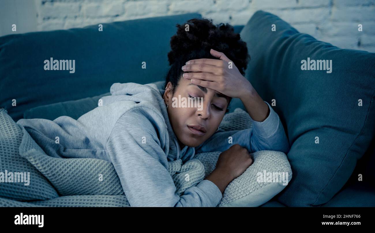 Depressed young attractive african american woman lying on sofa at home feeling sad tired and worried suffering depression stress and anxiety in menta Stock Photo