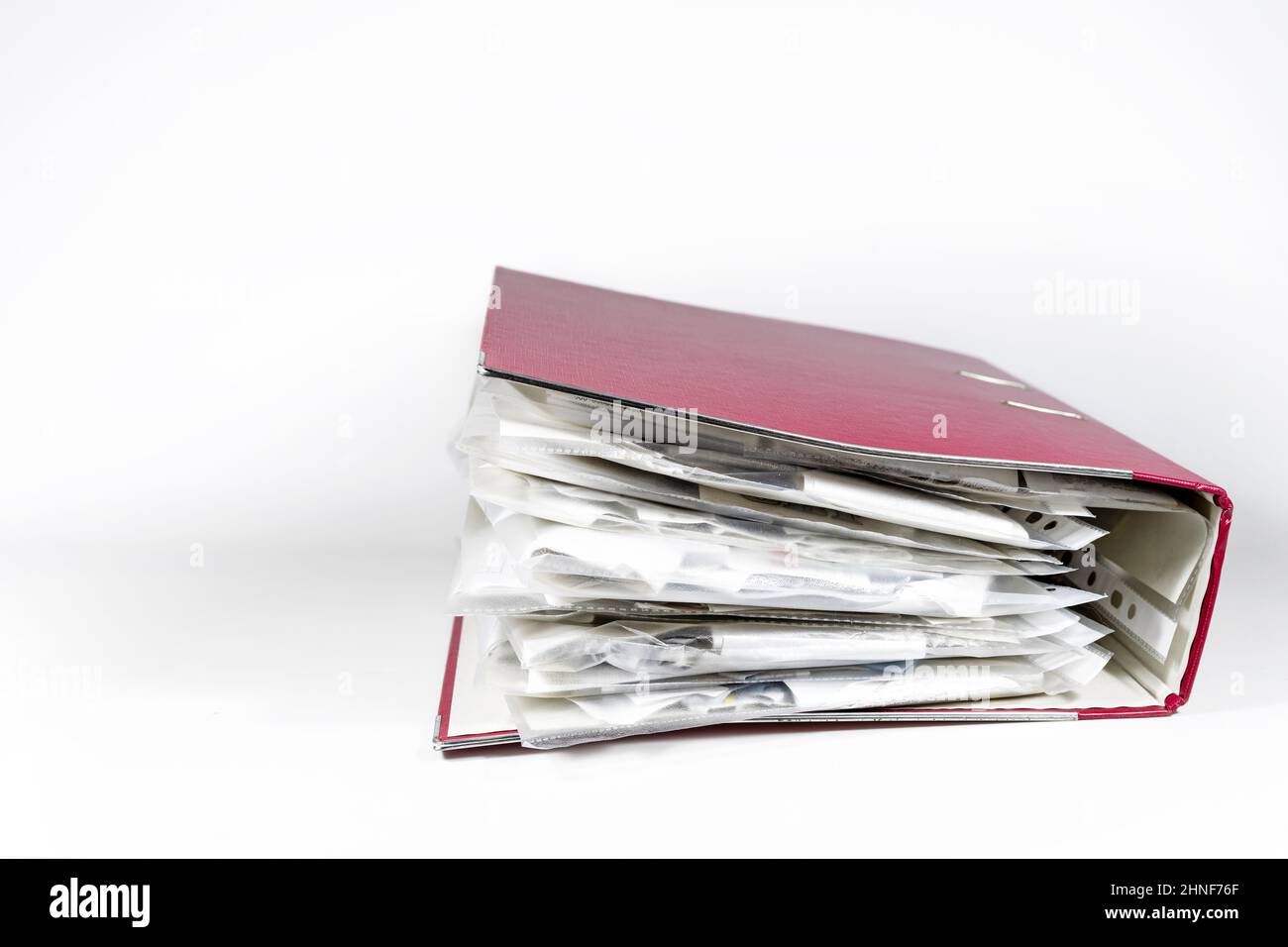 Red ring binder full of transparent punched pockets with receipts, office accounting concept, light gray background, copy space, selected focus, narro Stock Photo