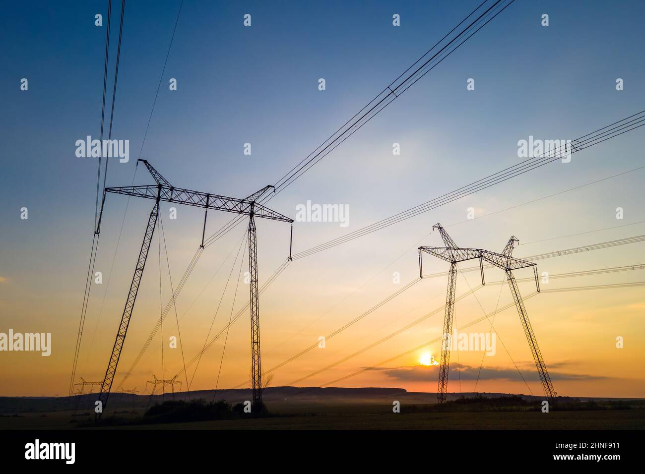 High voltage towers with electric power lines at sunset Stock Photo - Alamy