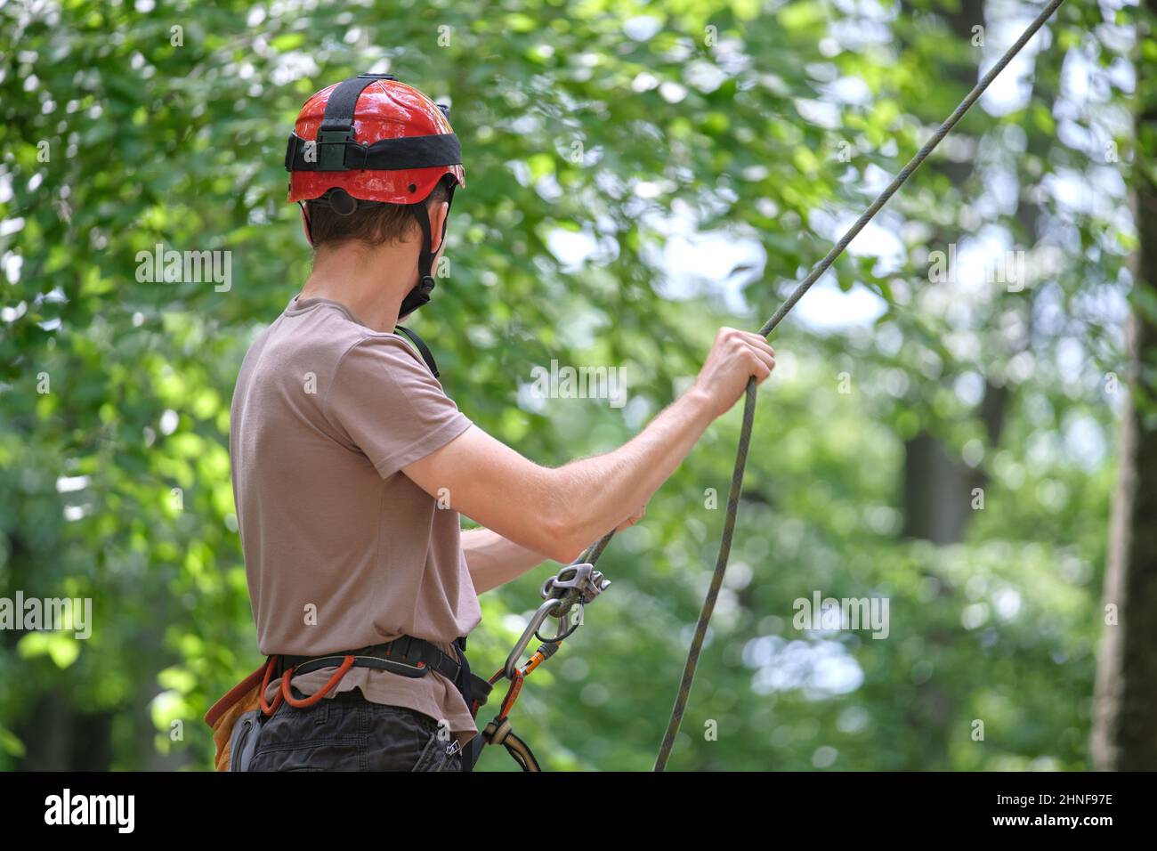 Man belays his partner climber with belaying device and rope. Climber's handsman holding