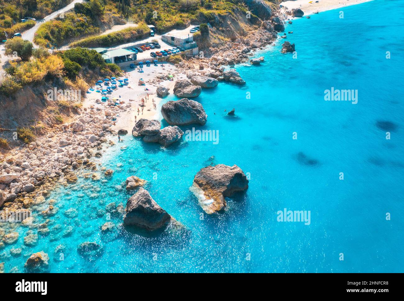 Aerial view of blue sea, beach with umbrellas, rocks in water Stock Photo