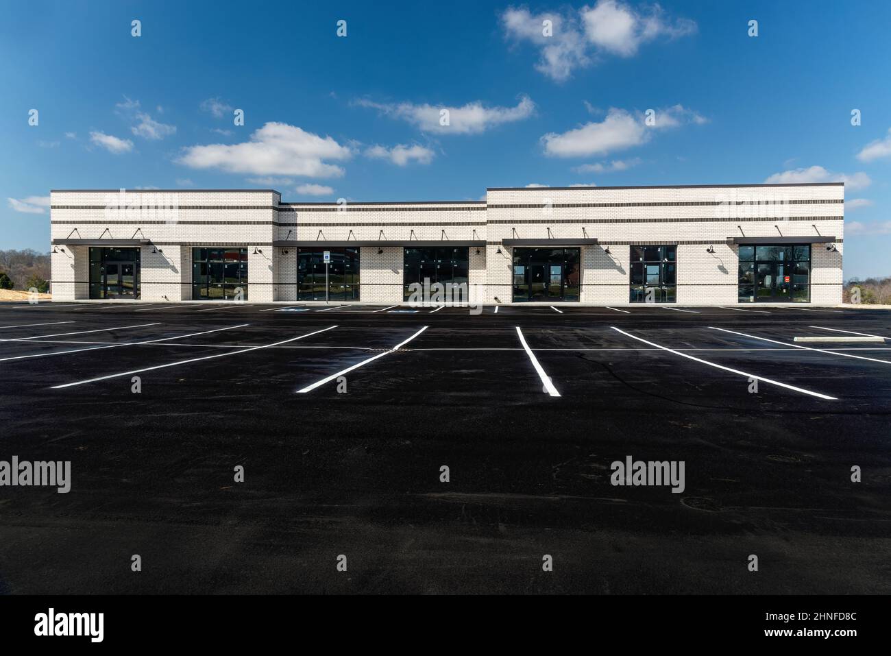 Horizontal shot of a new retail strip shopping center under construction with newly painted parking lot. Stock Photo