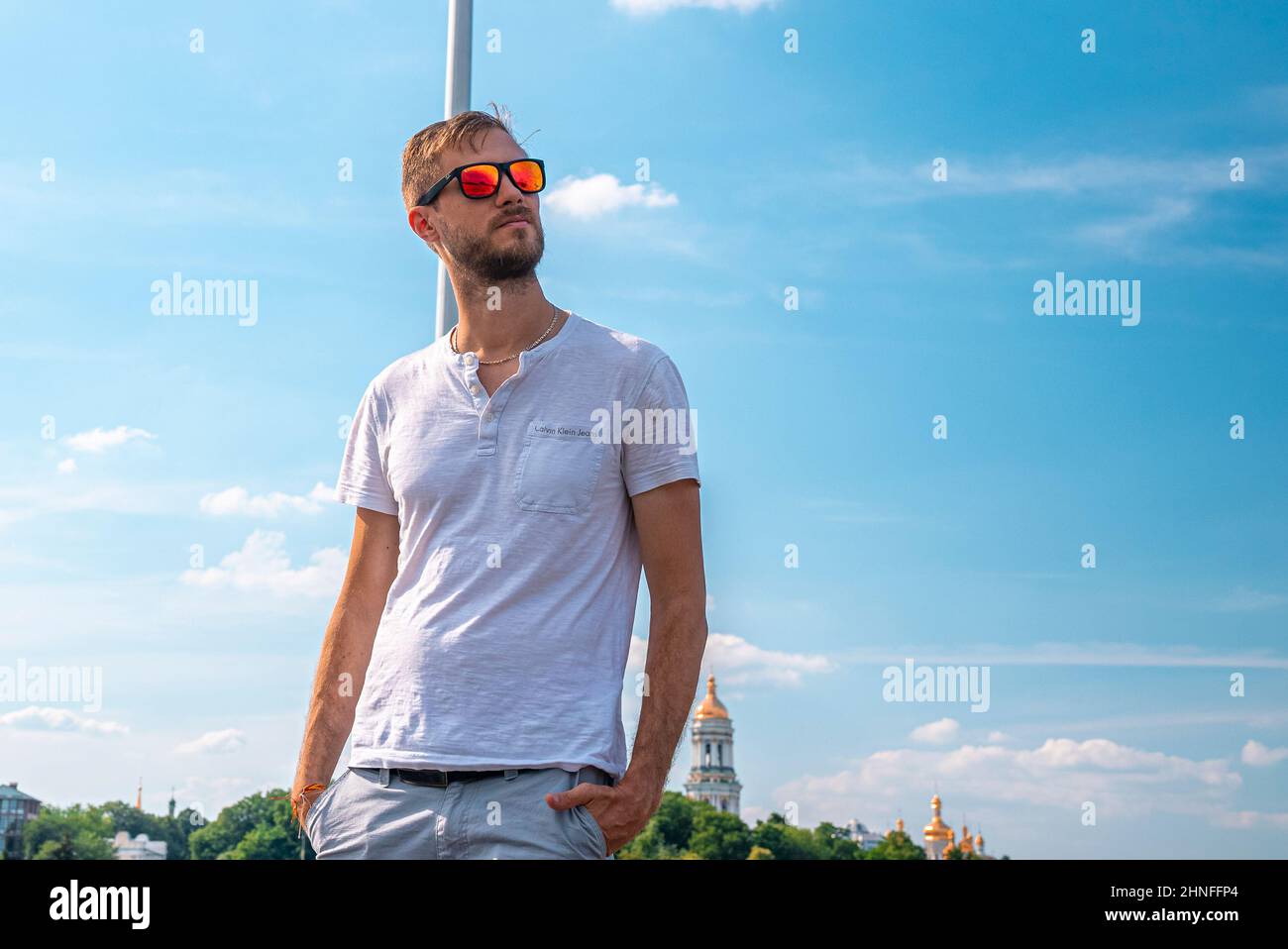 Stylish young man in sunglasses standing with hands in pockets Stock Photo