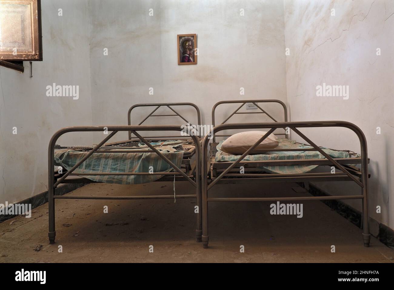 Two metal bedsteads with open window in narrow room, bedroom