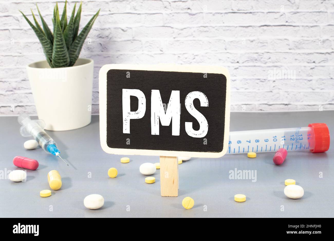 The inscription text on the grey board, PMS Premenstrual syndrome with hand drawn happy and sad emojis. Using color chalk pieces. Stock Photo