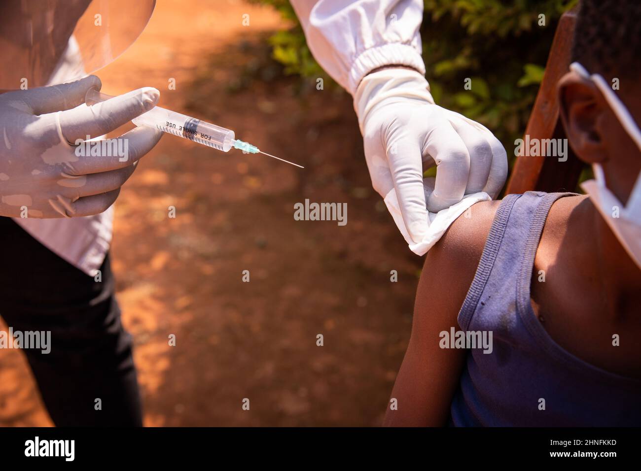 Close-up of a doctor's hand with a syringe about to inject the vaccine to a child in africa. Vaccination concept Stock Photo