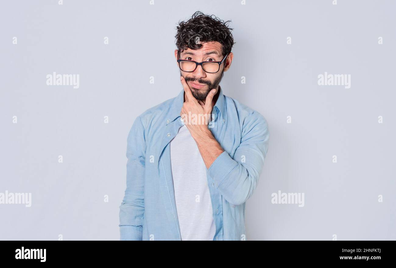 Man rubbing his beard with an expression of doubt, Image of a handsome bearded man with an expression of doubt Stock Photo