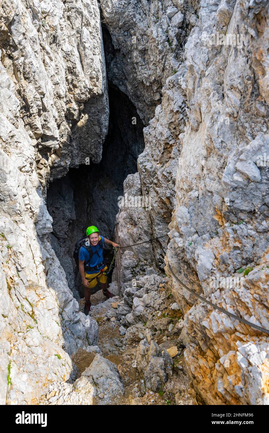 Young man climbing out of a rock hole, via ferrata Brudertunnel, Karwendel Mountains, Alpenpark