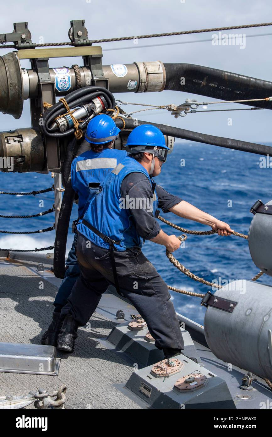 SOUTH CHINA SEA (Feb. 15, 2022) Boatswain’s Mate Seaman Jimenez Bello, front, from San Jose, California, and Boatswain’s Mate 3rd Class Ashley Iuli, from Los Angeles, rig a return messenger line aboard the Arleigh Burke-class guided-missile destroyer USS Dewey (DDG 105) during a replenishment-at-sea with the Military Sealift Command dry cargo and ammunition ship USNS Alan Shepard (T-AKE 3). Dewey is assigned to Destroyer Squadron (DESRON) 15 and is underway supporting a free and open Indo-Pacific. CTF 71/DESRON 15 is the Navy’s largest forward-deployed DESRON and the U.S. 7th Fleet’s principal Stock Photo