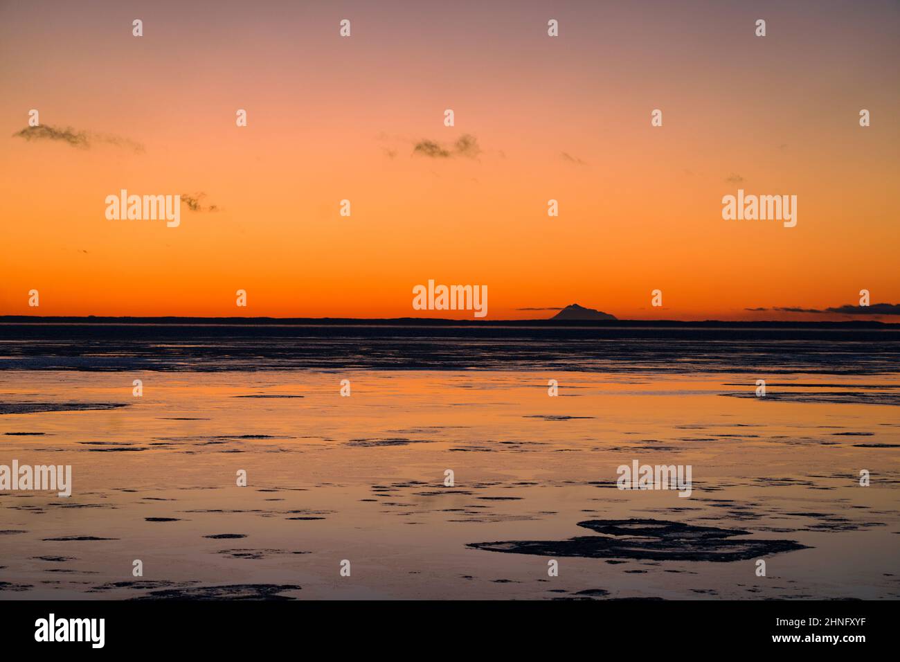 Sunset glows across Cook Inlet and behind Mount Redoubt from Anchorage, Alaska. Stock Photo