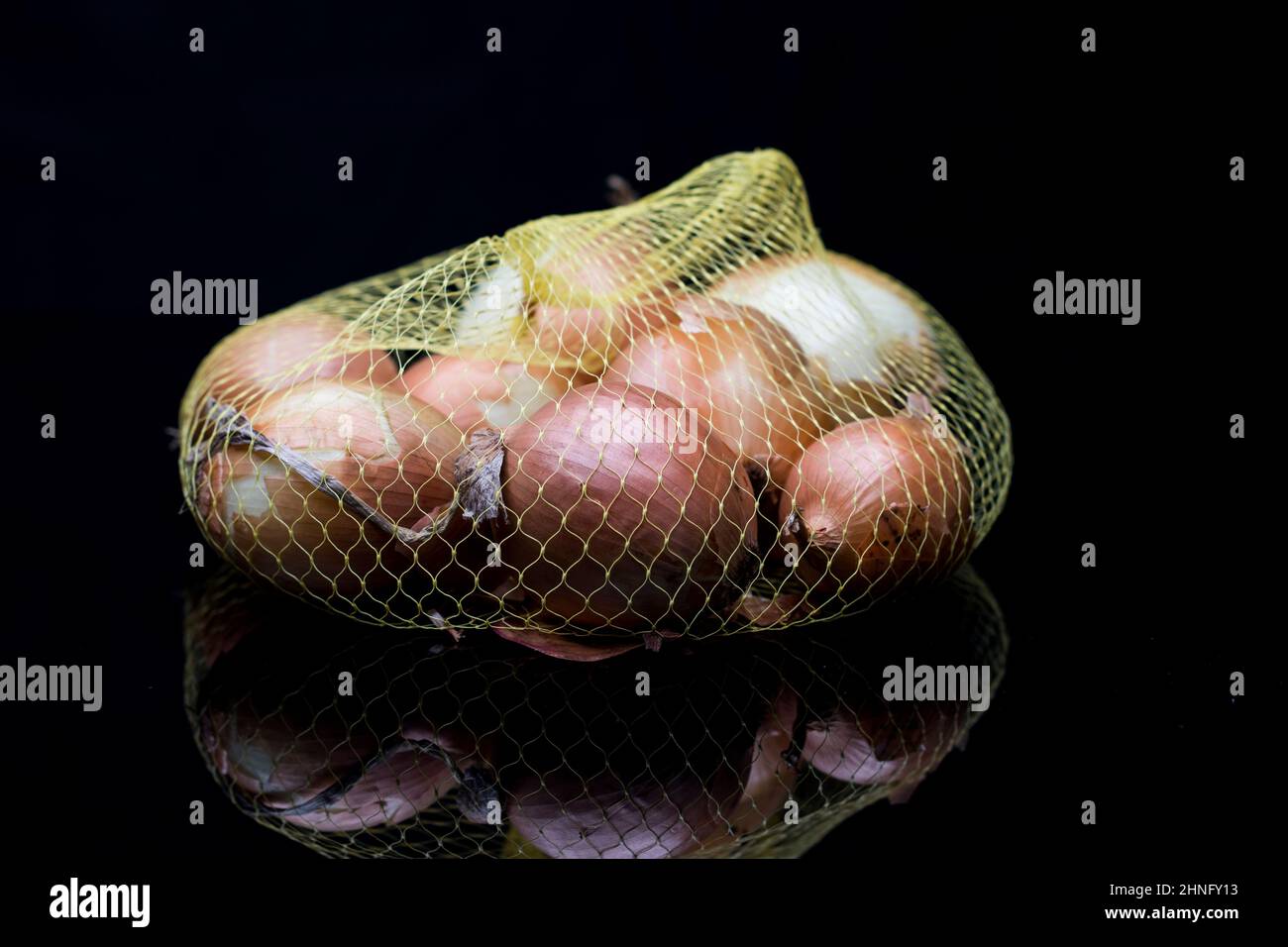 Cooking ingredients onions for cooking. Bag of brown onions with hand selecting one for cooking. Stock Photo