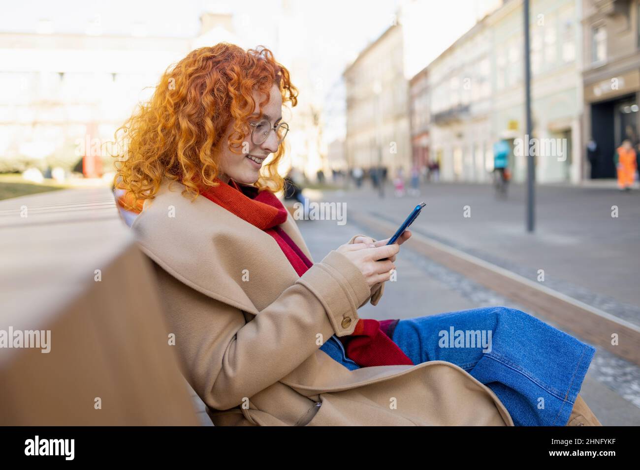 Curly woman using her phone in city center Stock Photo