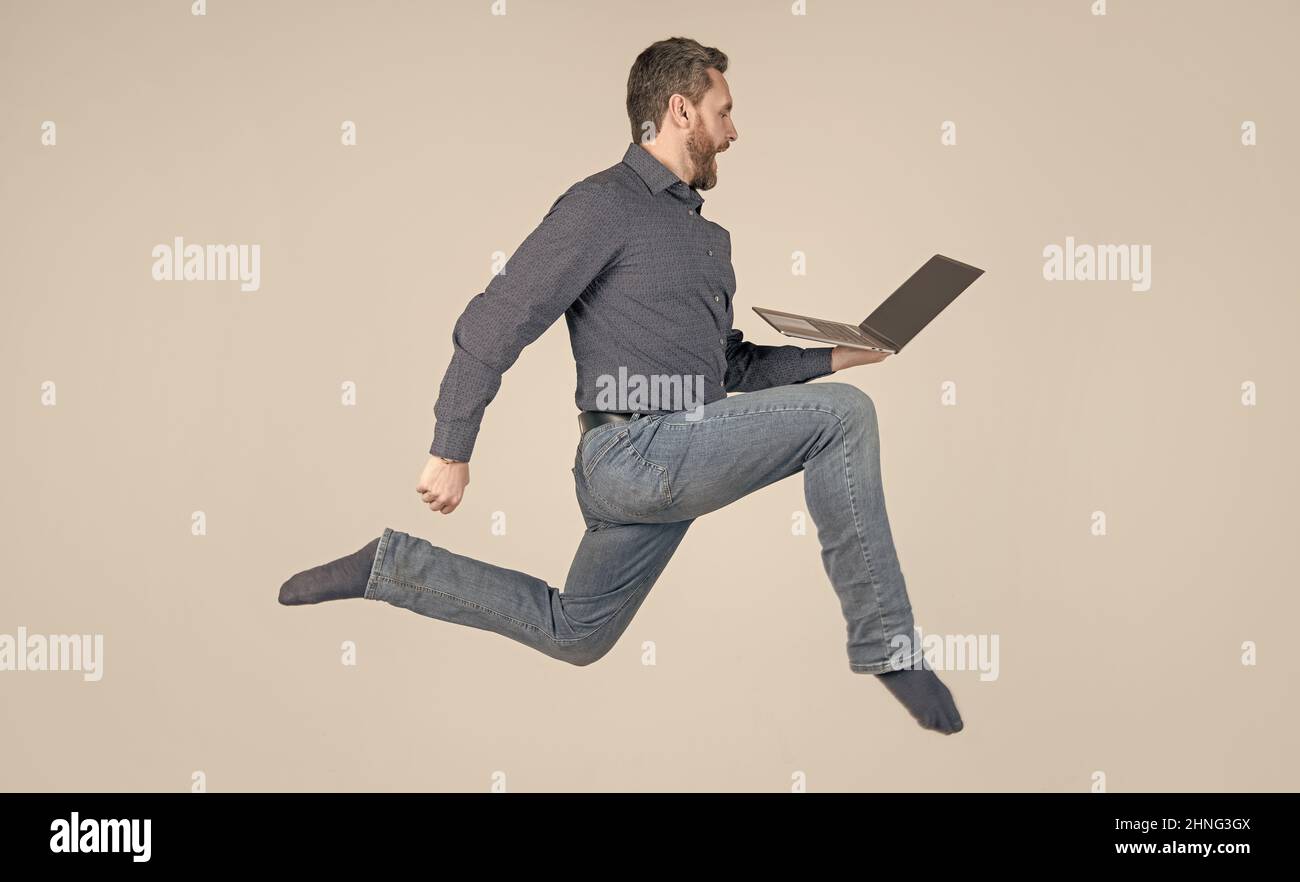 surprised energetic man running while working online on laptop hurry up for shopping, shopping. Stock Photo