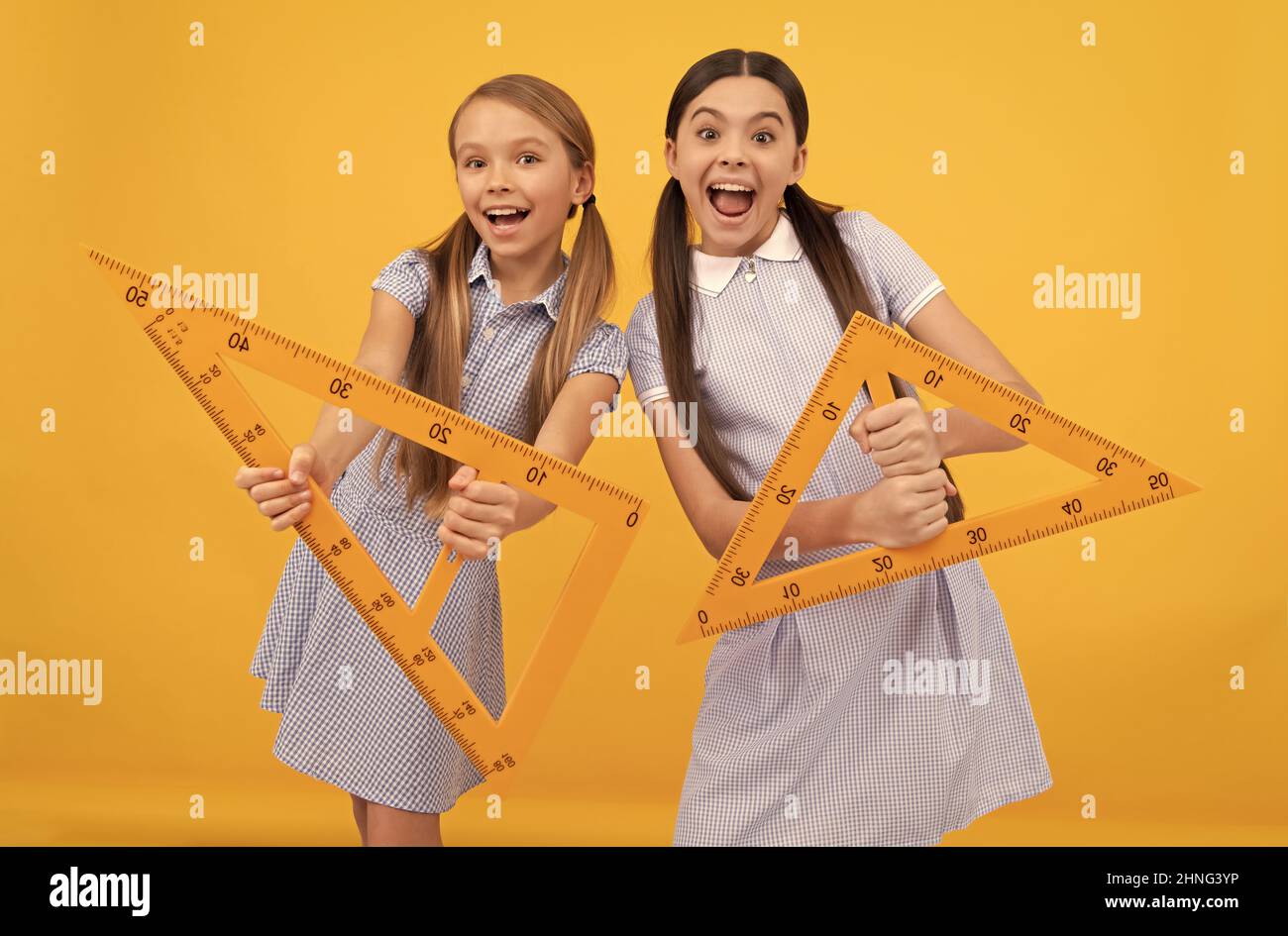 Learn what angles are. Happy teen girls hold triangular rulers. Geometry lesson. Preparing lesson Stock Photo
