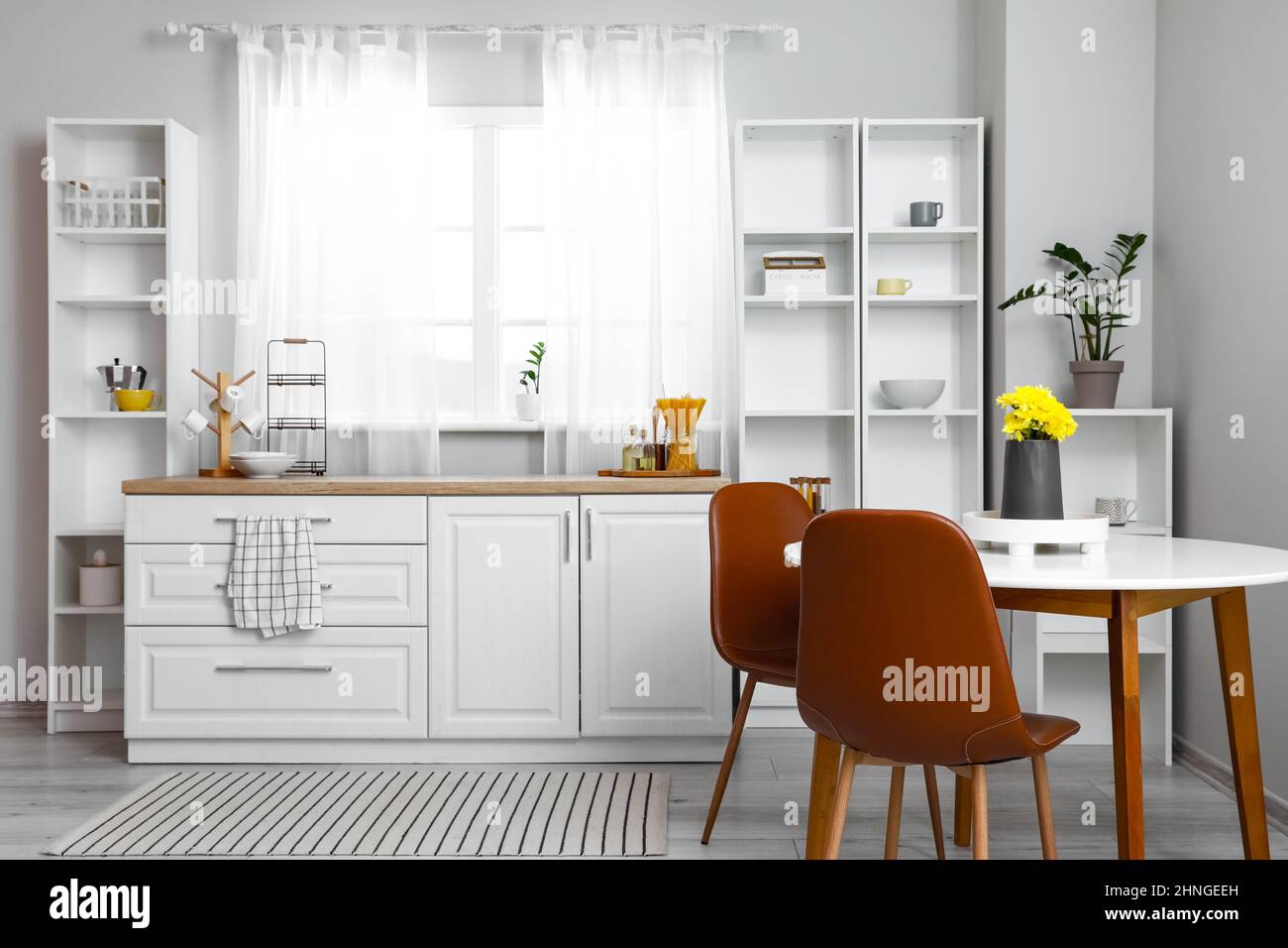 Interior of light kitchen with dining table and shelving unit Stock ...