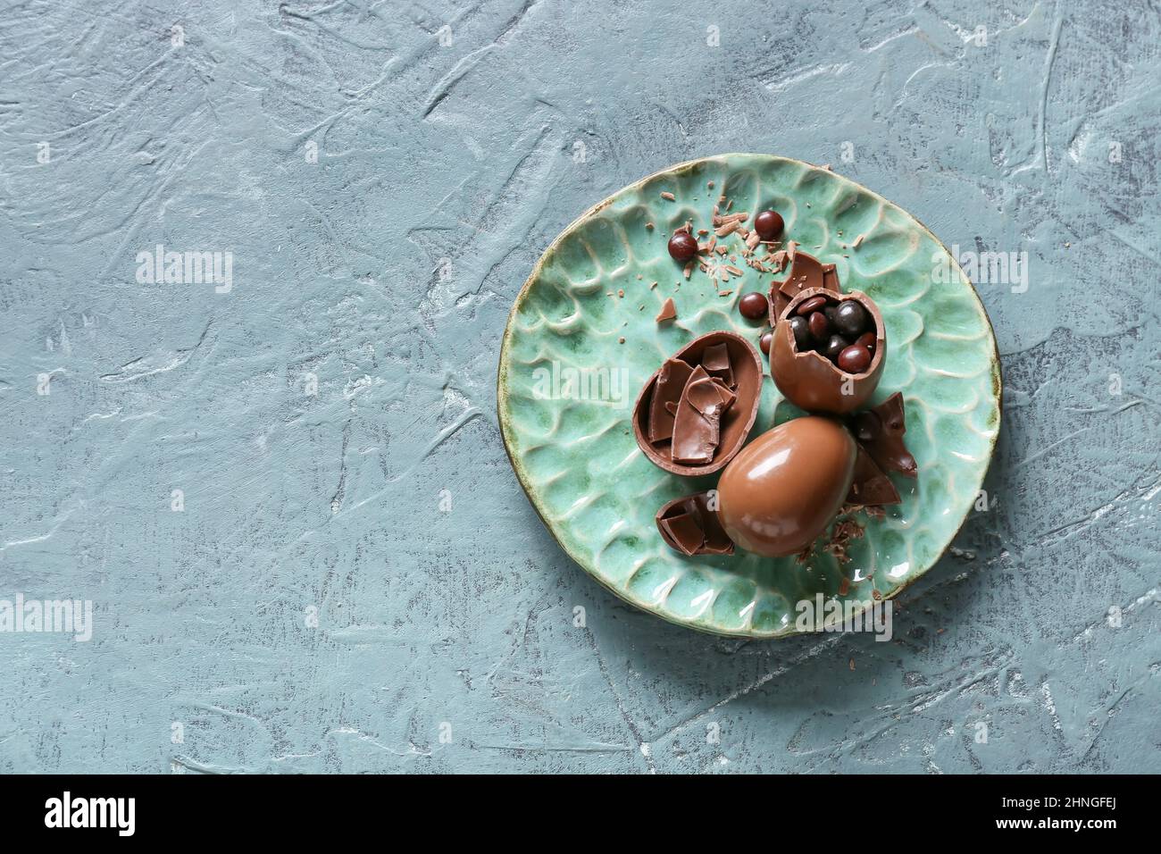 Plate with broken chocolate Easter eggs on color background Stock Photo