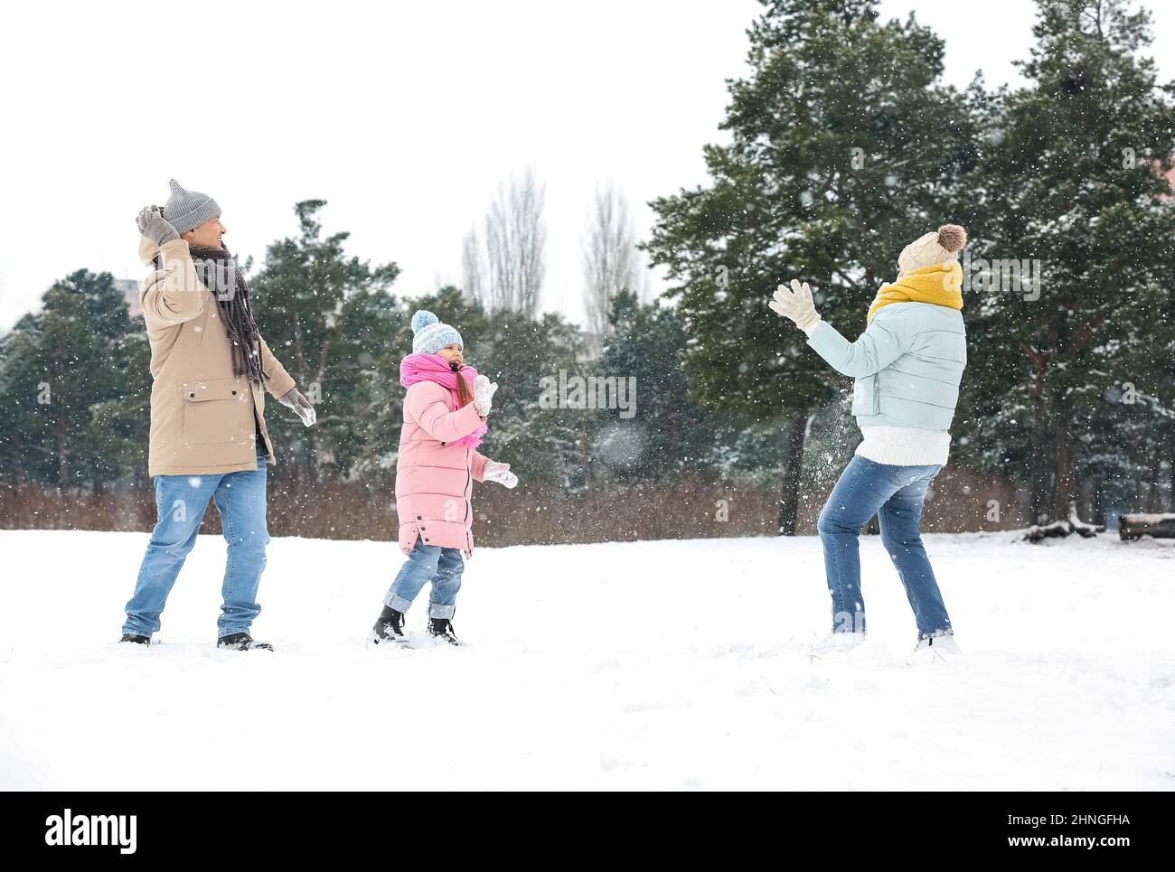Little girl and her grandparents throwing snowballs on snowy winter day