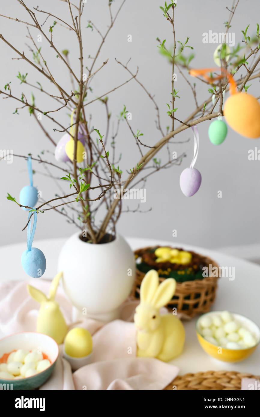 Tree branches decorated with Easter eggs on served table Stock Photo