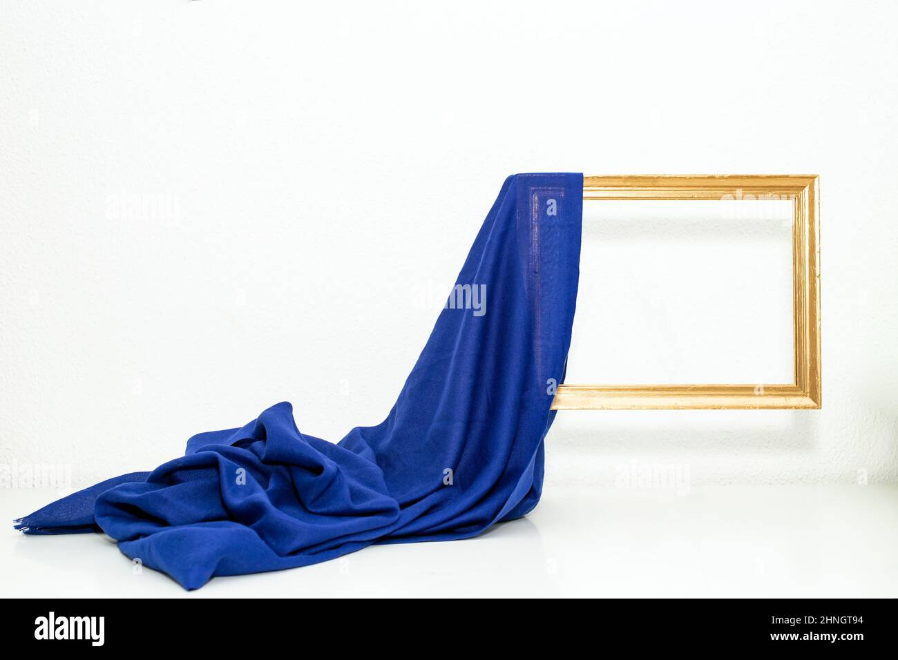 Blue fabric curtains unveiling a levitating golden empty frame, on white background, wallpaper design Stock Photo