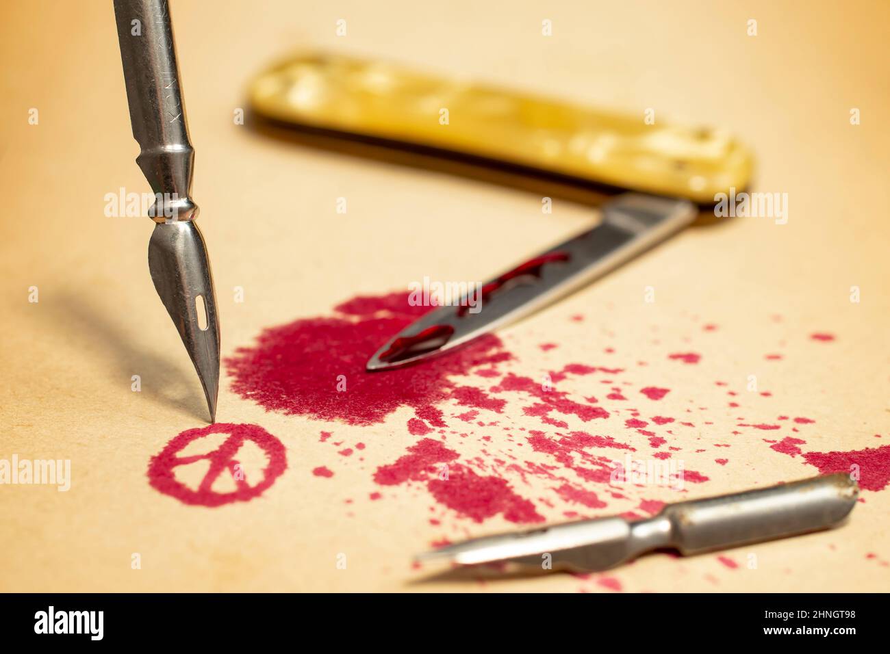 Dip pen nib and spilled red ink forming peace symbol,  depicting that a pen is mightier than a sword. Selective focus photography Stock Photo