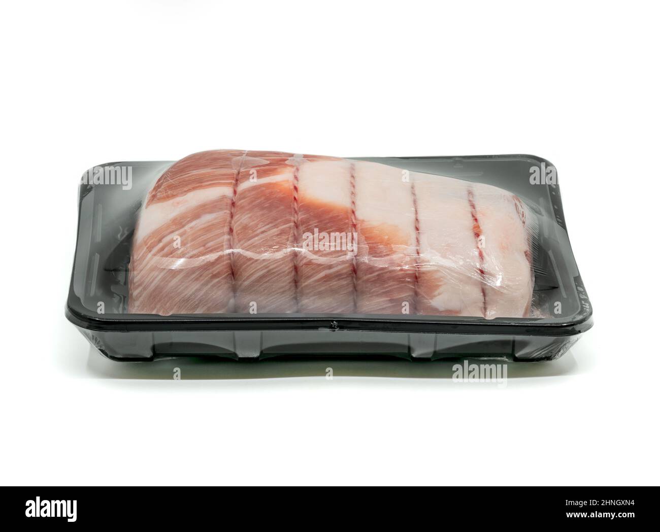 Close up raw cut of pork loin, tied up and rolled with butcher's string in black plastic container, wrapped with plastic film preservation for sale on Stock Photo