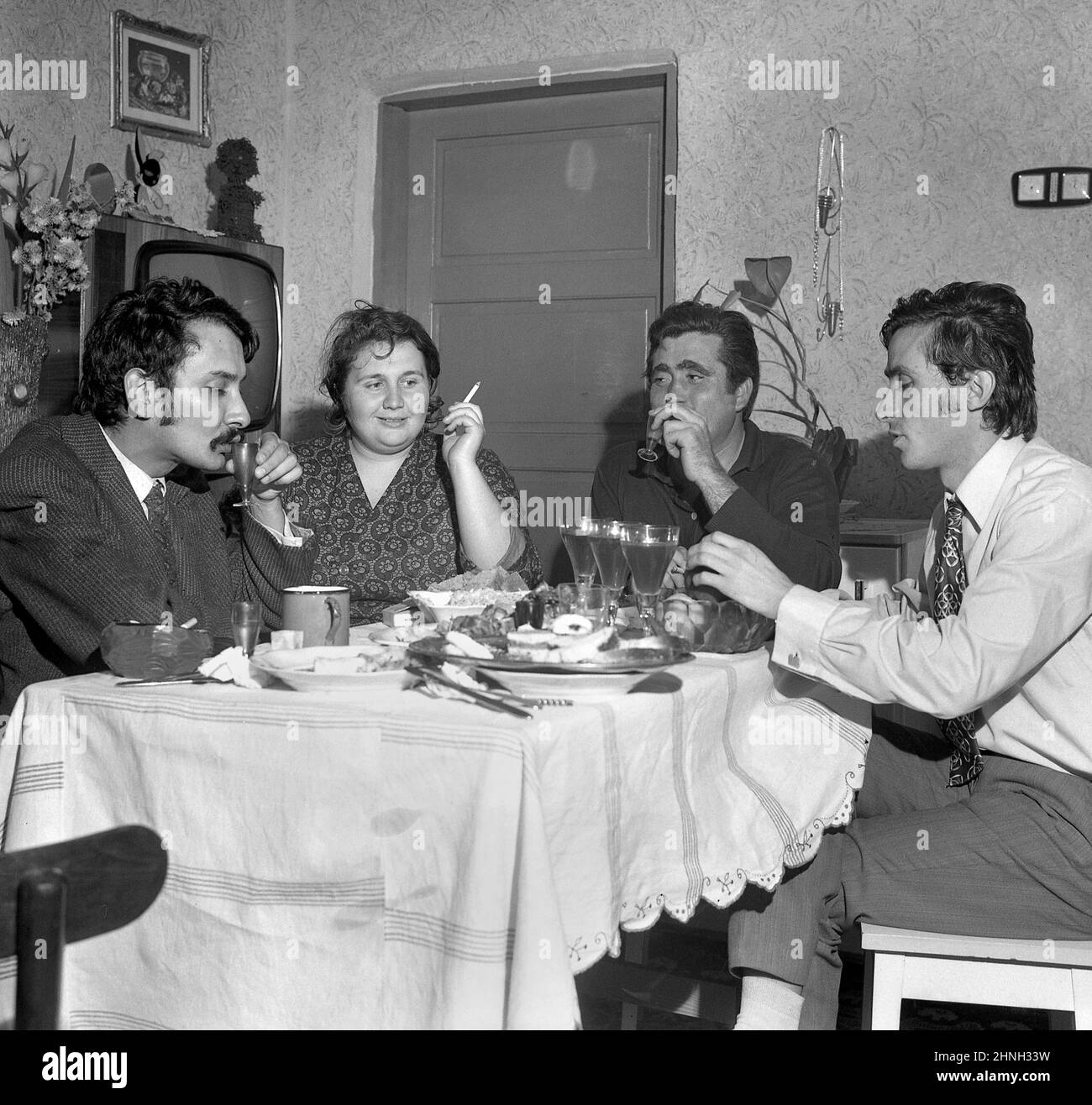 Romania, 1972. People gathered around the table in the living room of a communist- era apartment. Stock Photo