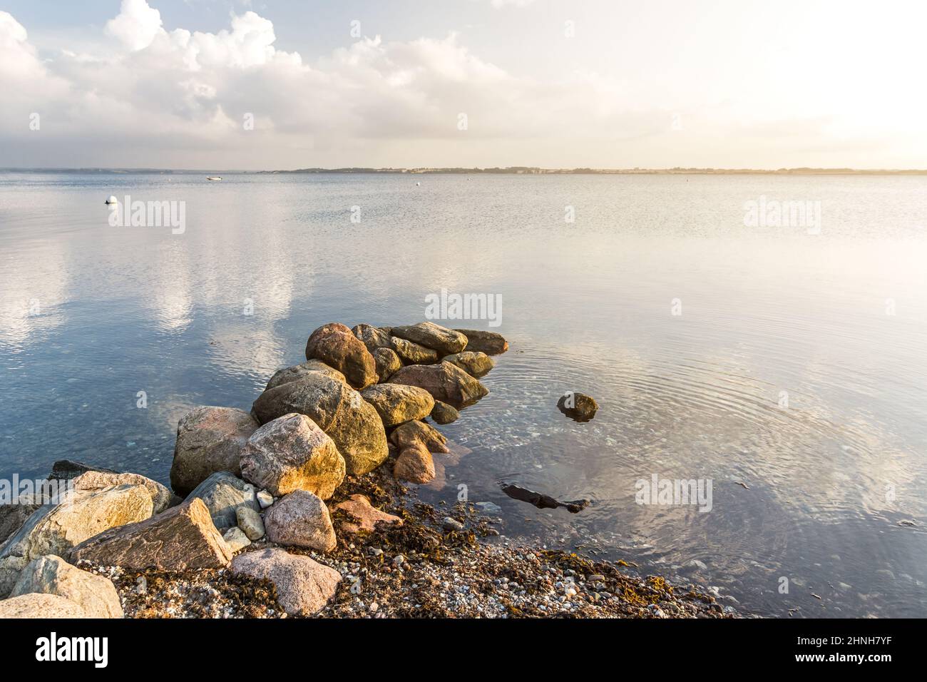 Rocks at a pebble beach at the calm Baltic sea in the peaceful morning light Stock Photo