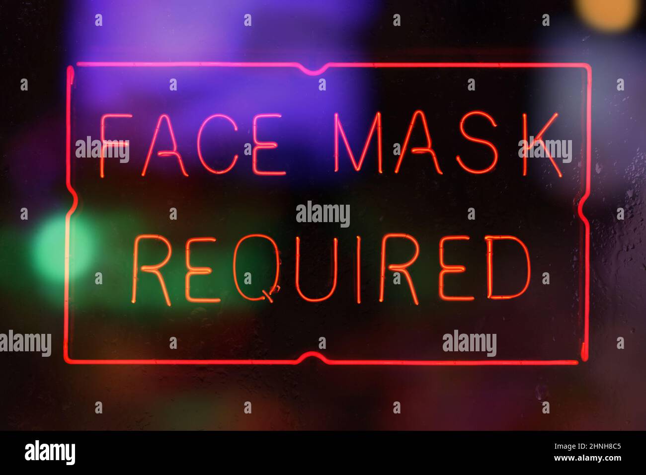 Neon Face Mask Required Sign in Rainy Store Window Stock Photo