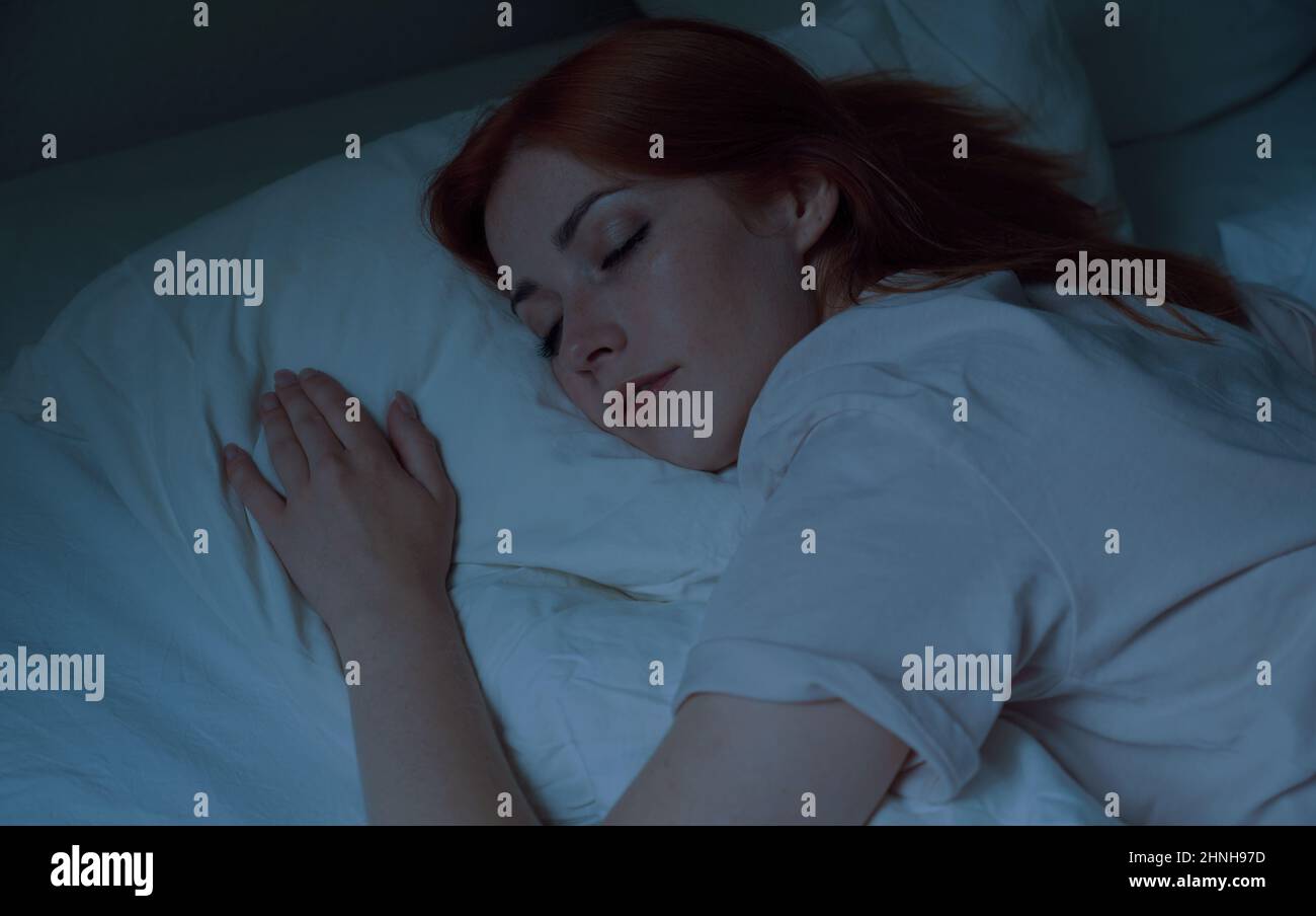 young woman asleep in bed at night Stock Photo