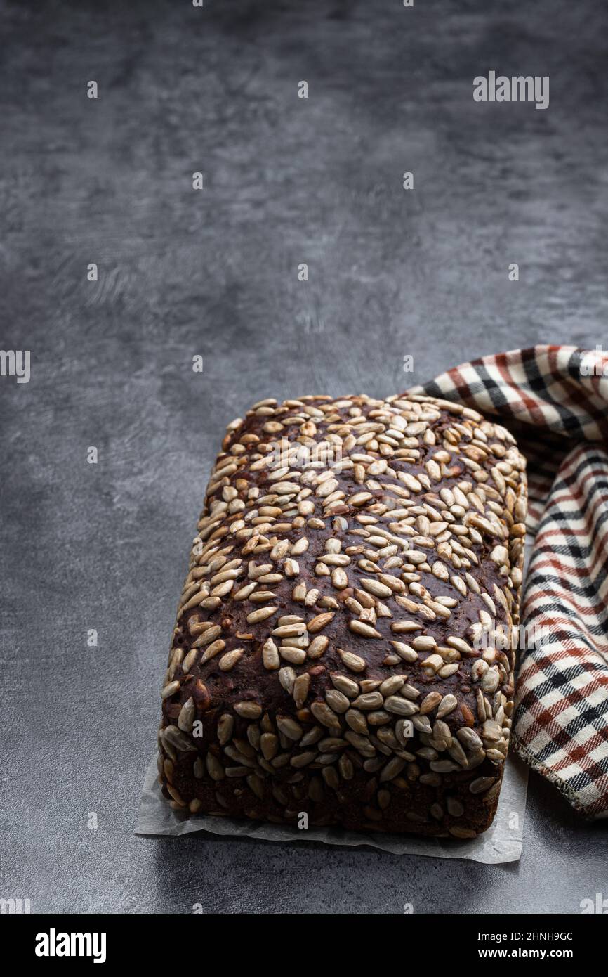 Homemade dark rye bread with sunflower seeds on gray stone background