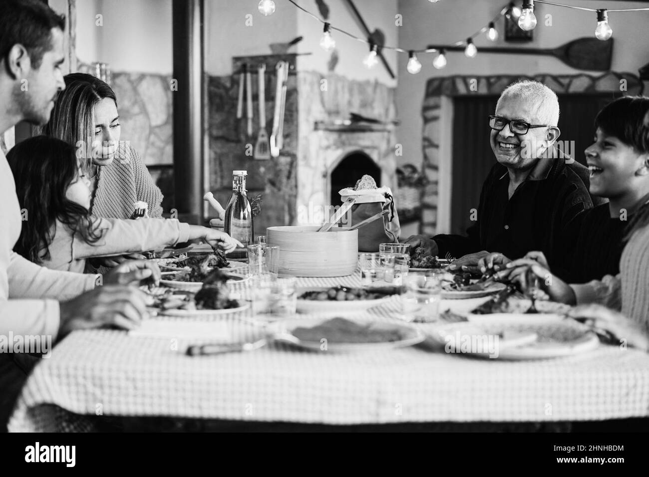 Happy latin family having fun eating together at home - Focus on mother face - Black and white editing Stock Photo