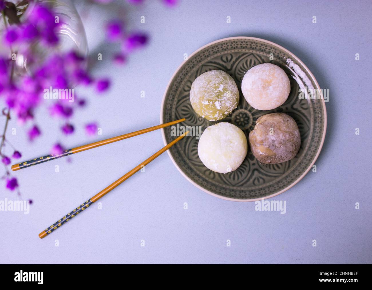 Traditional Japanese dessert mochi in rice dough on gray plate, food chopsticks. Stock Photo