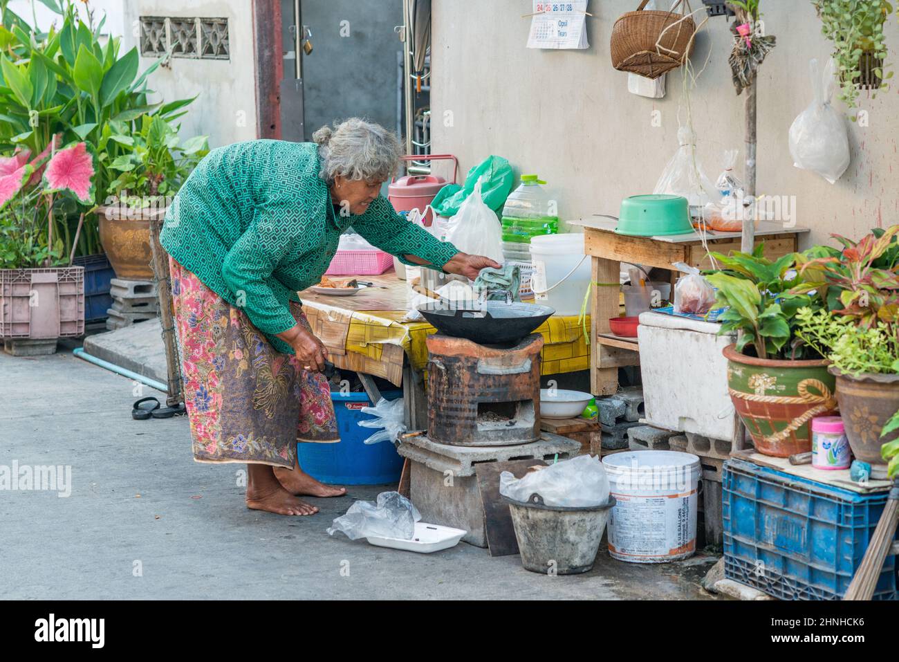 Elderly lady cooking in the street in Hua Hin. This is an old fishing village that became one of the most popular travel destinations in Thailand. Stock Photo