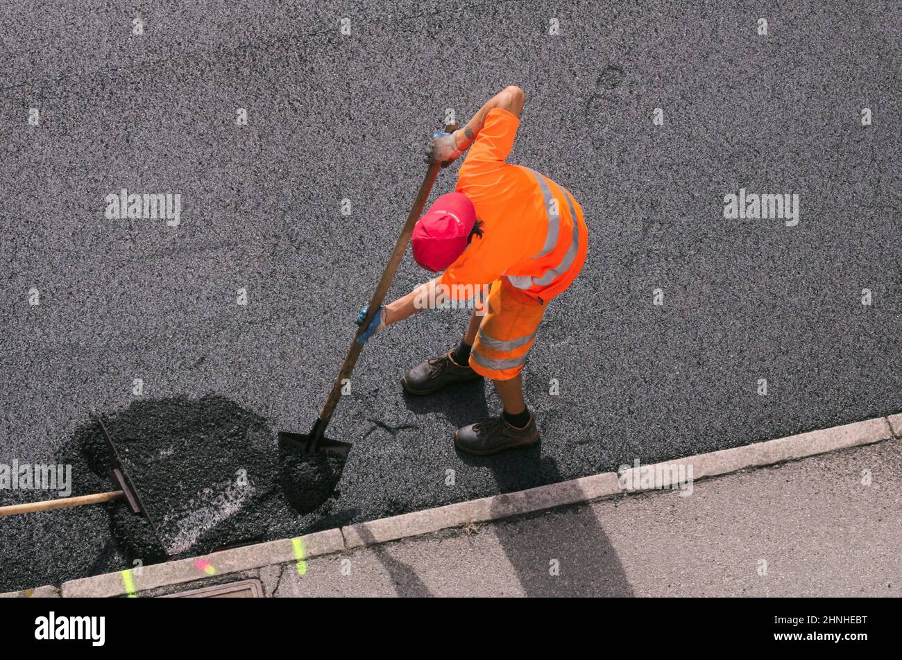 asphalt worker with his shovel during road resurfacing Stock Photo