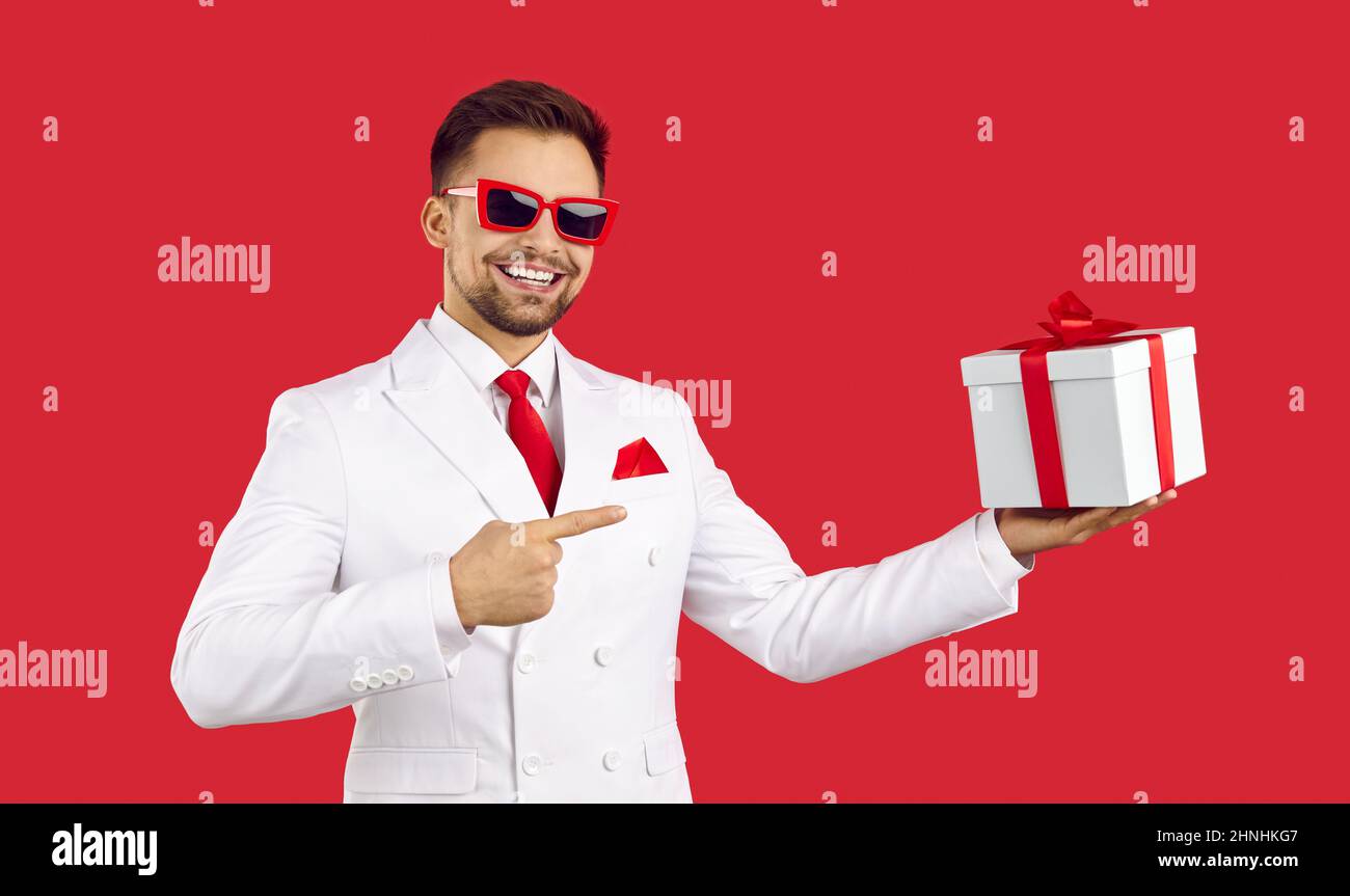 Smiling man in suit point at wrapped gift box Stock Photo