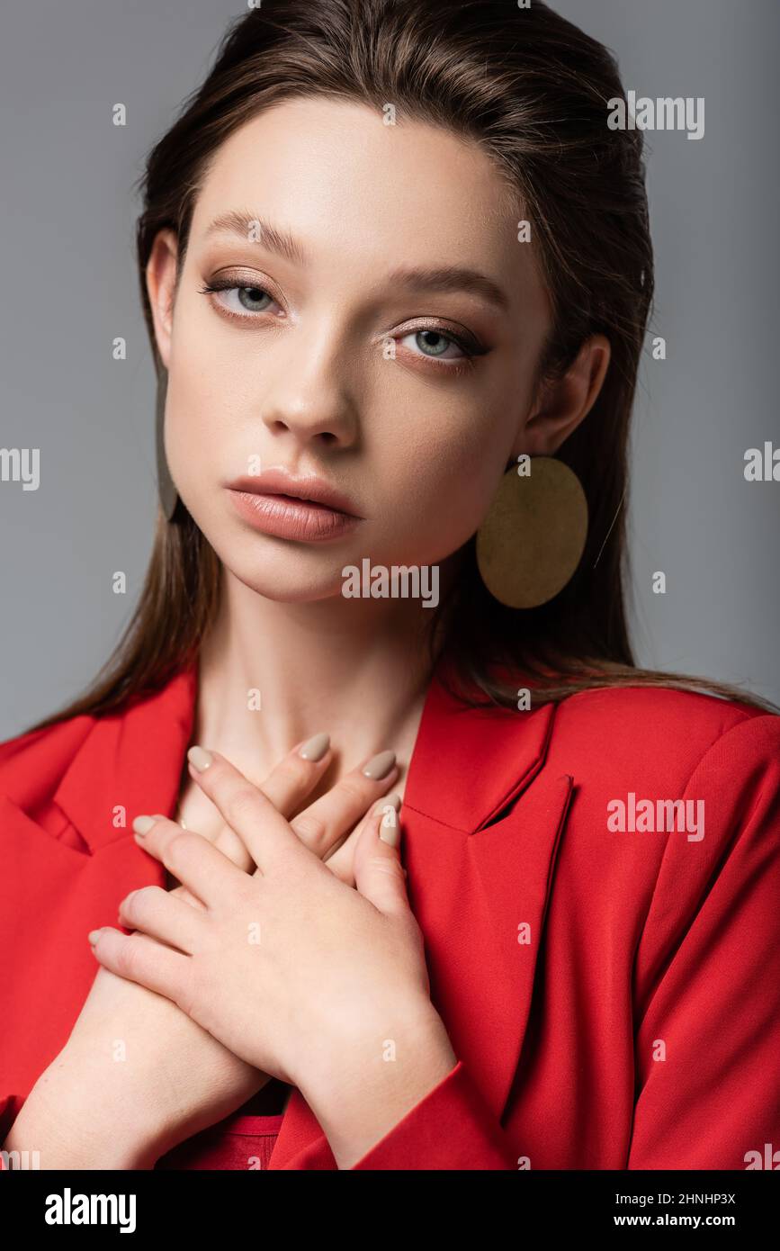 pretty model in red blazer looking at camera isolated on grey Stock Photo