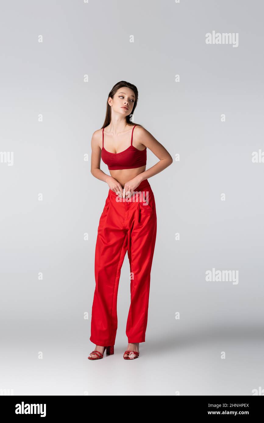 full length of pretty model in red outfit looking away on grey Stock Photo