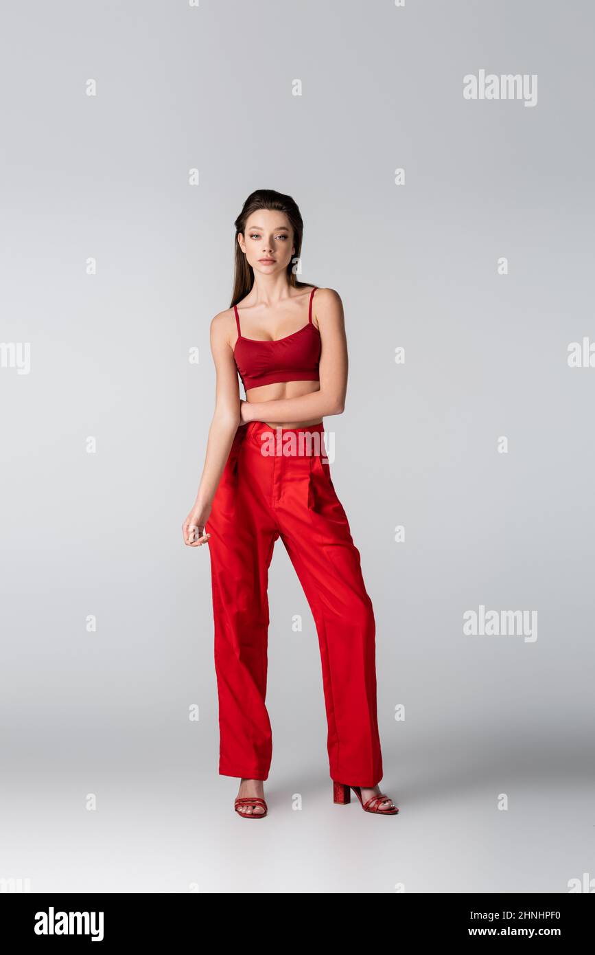 full length of young pretty model in red outfit posing on grey Stock Photo