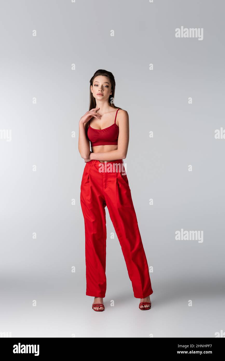 full length of pretty model in red outfit posing on grey Stock Photo