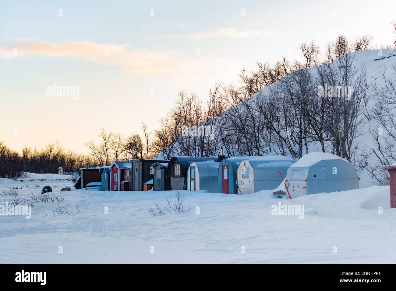 row of small recreational cabins in winter time in the north of Sweden Stock Photo