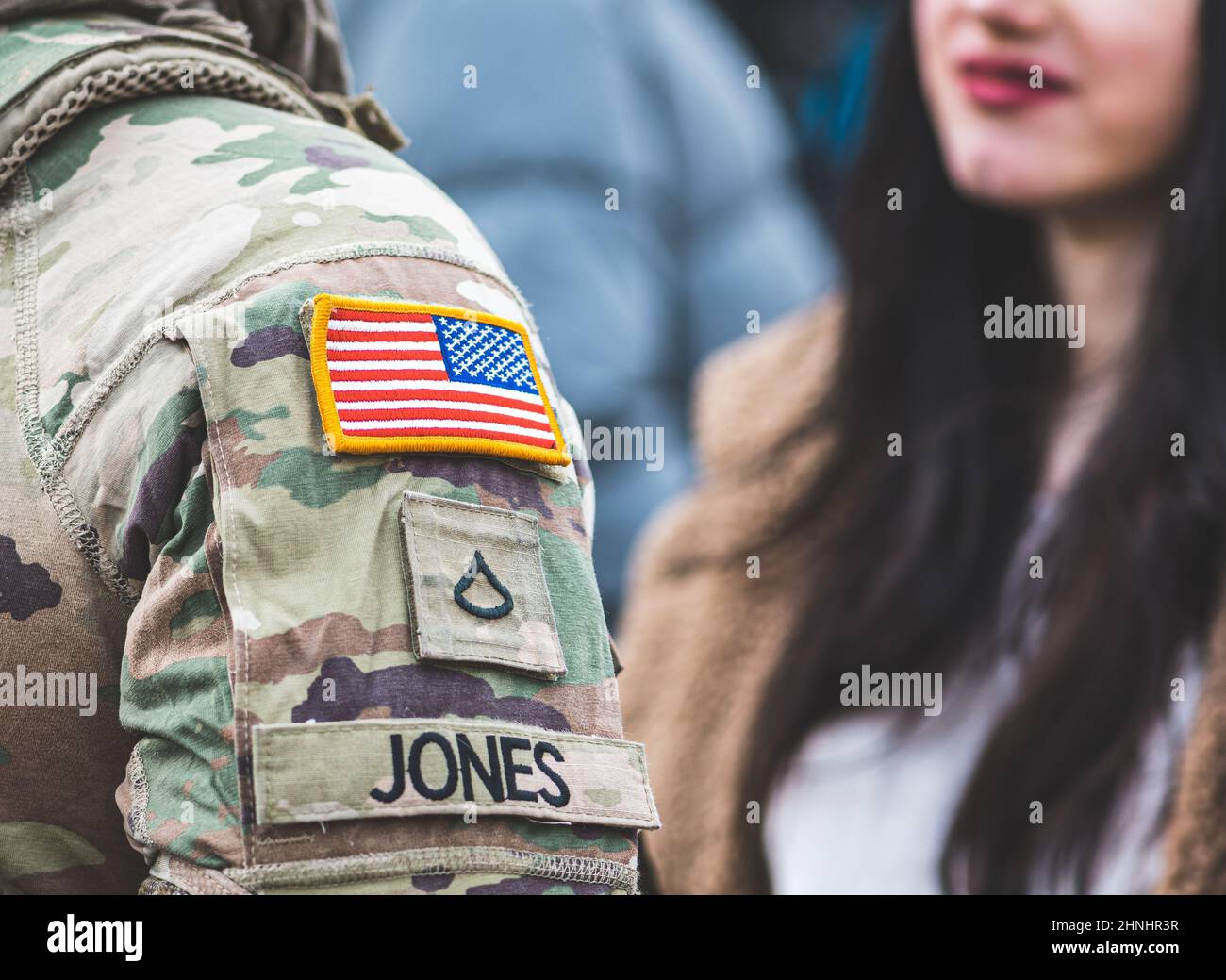 Flag of United States Marine Corps, USA or US army and symbols on an uniform of a soldier talking with a beautiful girl with red lips and black hair Stock Photo