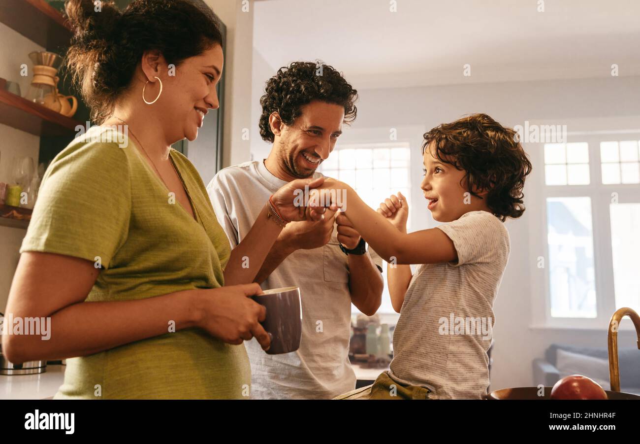 Happy parents spending some quality time with their son at home. Mom and dad playing with their young son in the morning. Young family of three smilin Stock Photo
