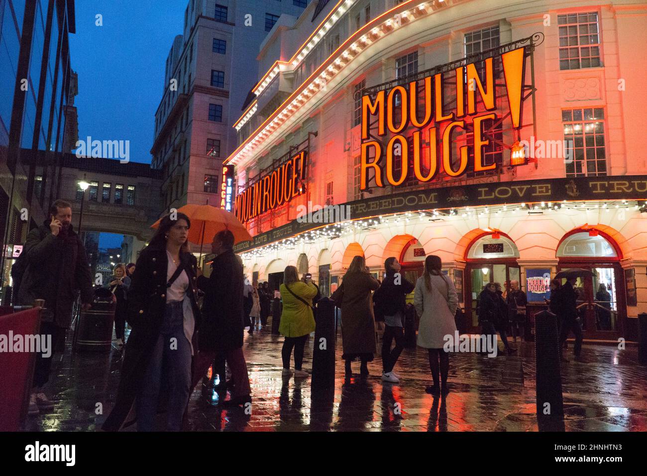 London, Uk, 16 February 2022: The Piccadilly Theatre in Soho is illuminated for the musical show Moulin Rouge! and the red lights reflect off wet streets on a rainy evening. With covid restrictions relaxed in England the West End has been busier during half term than for a long time and the hospitality and arts sectors are benefitting from the rebound. Anna Watson/Alamy Live News Stock Photo