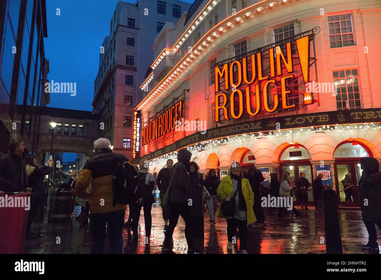 London, Uk, 16 February 2022: The Piccadilly Theatre in Soho is illuminated for the musical show Moulin Rouge! and the red lights reflect off wet streets on a rainy evening. With covid restrictions relaxed in England the West End has been busier during half term than for a long time and the hospitality and arts sectors are benefitting from the rebound. Anna Watson/Alamy Live News Stock Photo