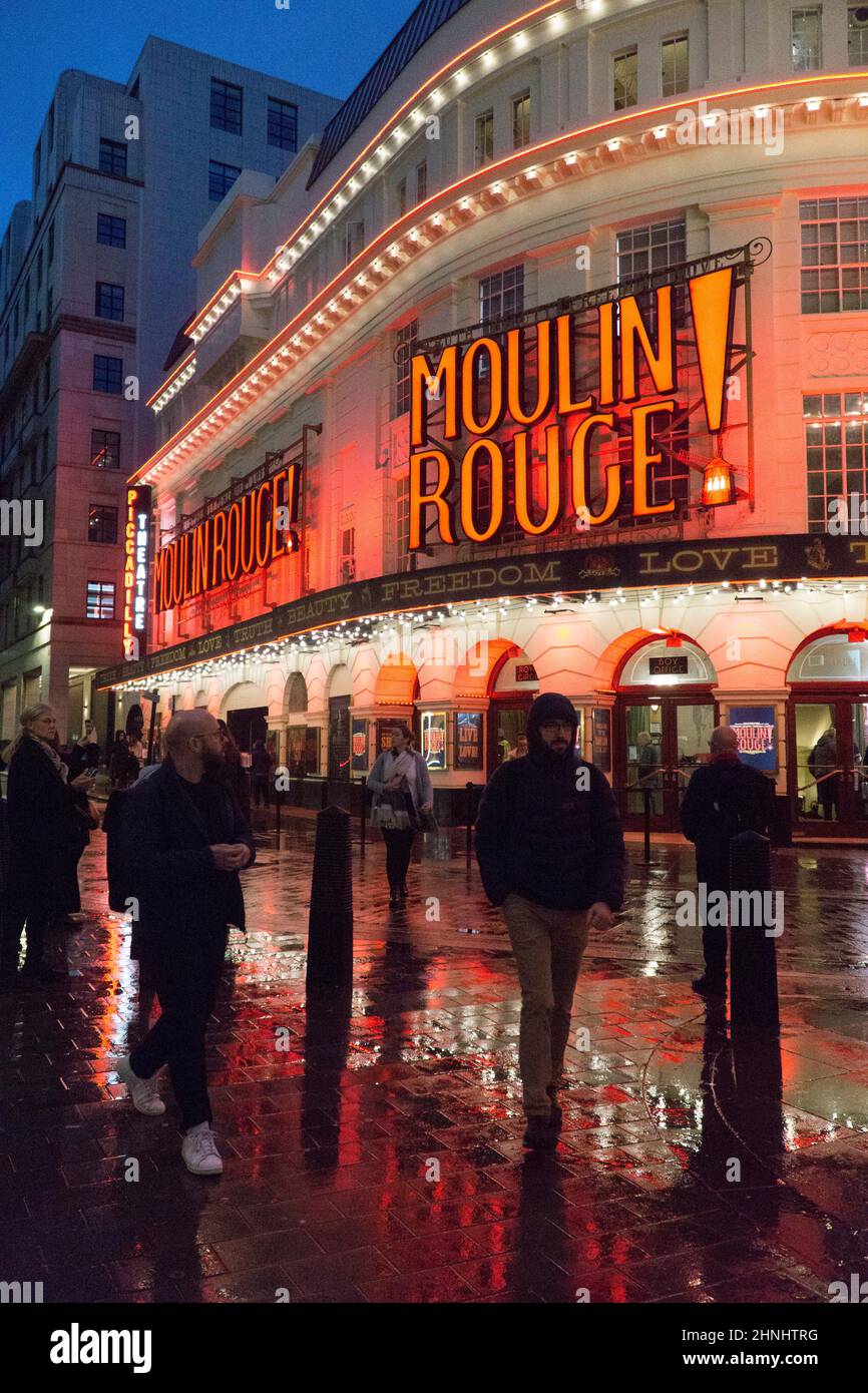 London, Uk, 16 February 2022: The Piccadilly Theatre in Soho is illuminated for the musical show Moulin Rouge! and the red lights reflect off wet streets on a rainy evening. With covid restrictions relaxed in England the West End has been busier during half term than for a long time and the hospitality and arts sectors are benefitting from the rebound. Anna Watson/Alamy Live News Stock Photo