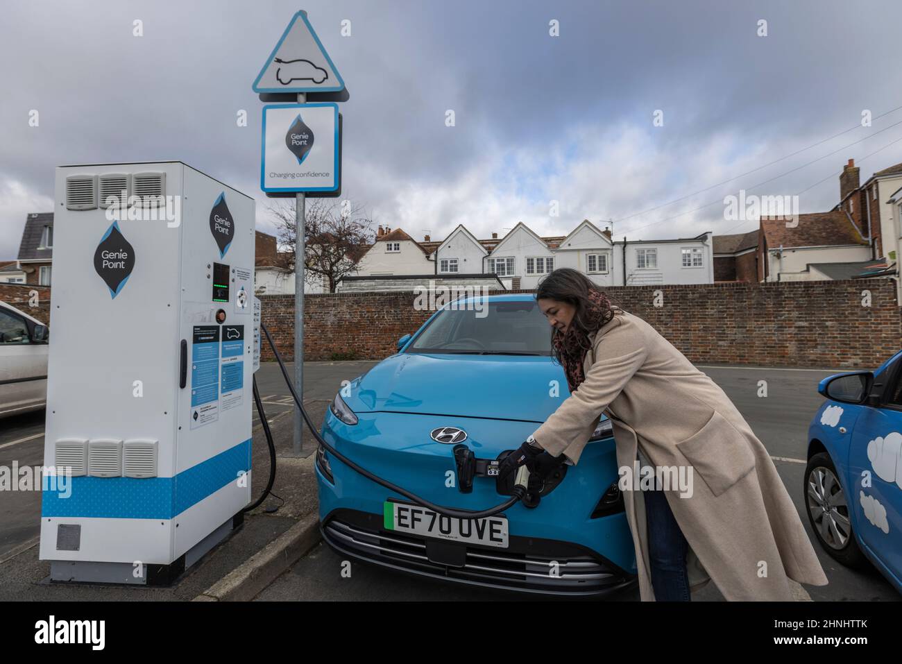 Middle aged lady using 'GeniePoint EV Charging' vehicle charging point in Hampshire , England, United Kingdom Stock Photo